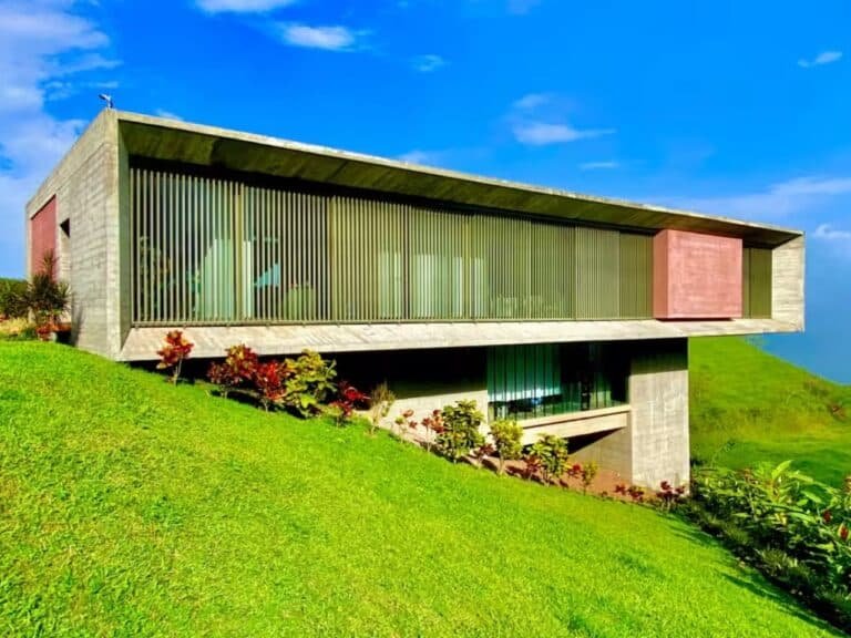Exterior view of John Desarzen's complex on the hillside in Atenas, Costa Rica, highlighting exposed concrete and suspended roofs.