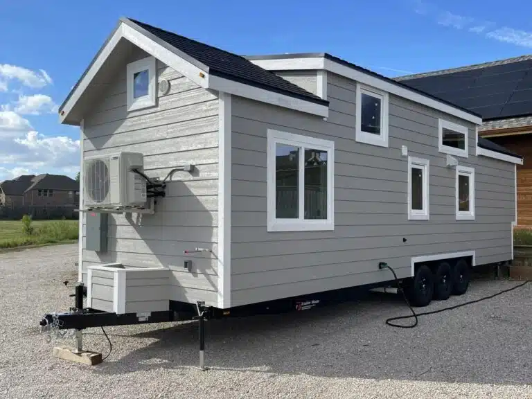 Exterior view of New Chapter tiny home on a triple-axle trailer, highlighting increased width and practical mobility for small-space living.