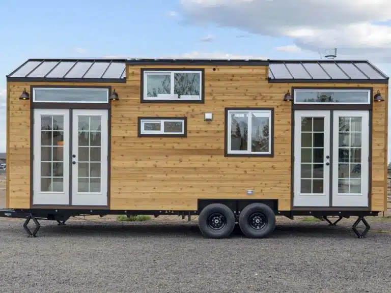 Exterior view of Shasta tiny house on double-axle trailer surrounded by nature