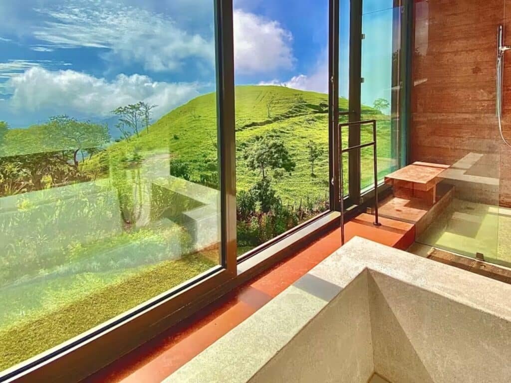 Exterior view of John Desarzen's complex on the hillside in Atenas, Costa Rica, highlighting exposed concrete and suspended roofs.