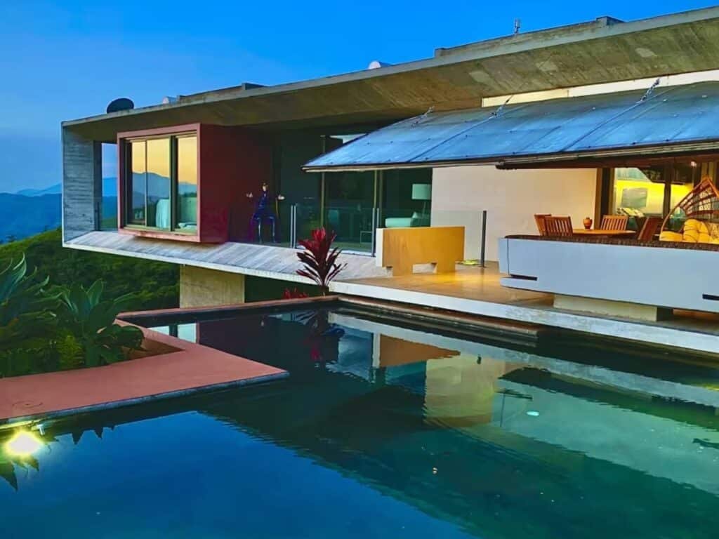 Exterior view of John Desarzen's complex on the hillside in Atenas, Costa Rica, highlighting exposed concrete and suspended roofs.