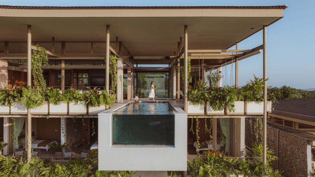 Comprehensive view of Nuri Villa showcasing modern architectural design, seamless integration of indoor and outdoor spaces, green terraces, suspended pool, natural materials, cultural interior details, panoramic ocean views, sustainable construction, and immersive living experience connecting nature, architecture, and local culture.