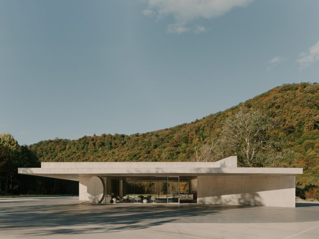 Exterior architectural view of the pavilion showing the floating concrete roof and surrounding landscape.