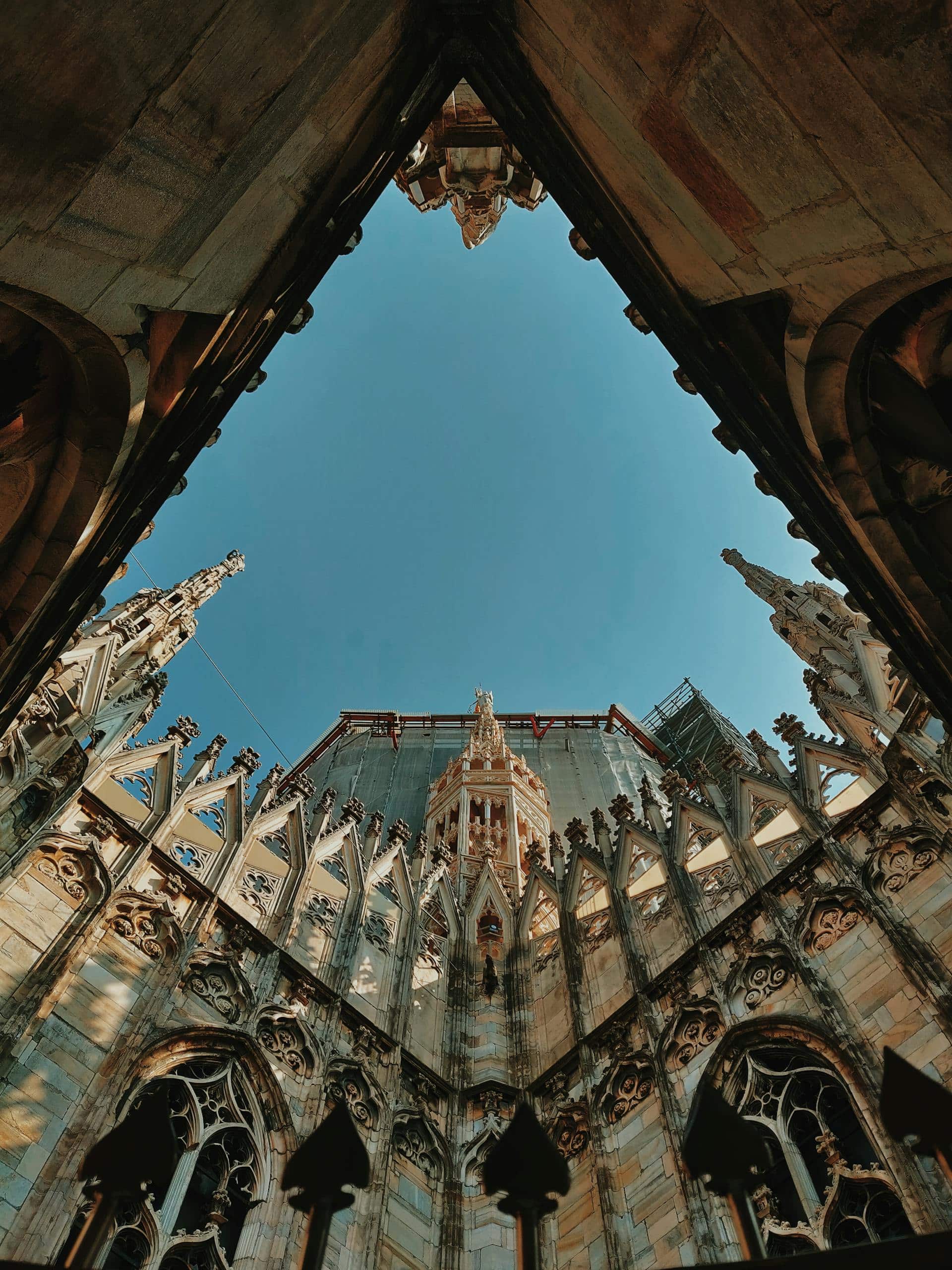Low angle view of a gothic cathedral's exterior with intricate architectural details and a clear sky backdrop.