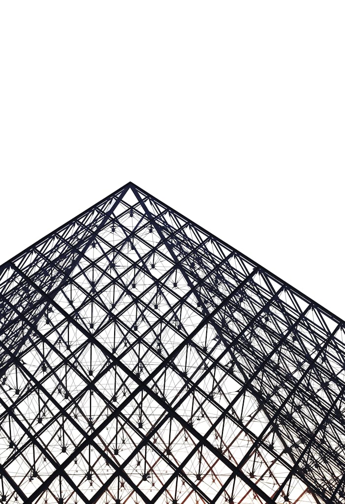 Low angle view of the Louvre Pyramid structure in Paris highlighting its geometric steel design.