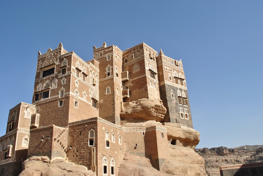 Majestic Dar al-Hajar rock palace in Yemen under a clear blue sky, showcasing unique architecture.