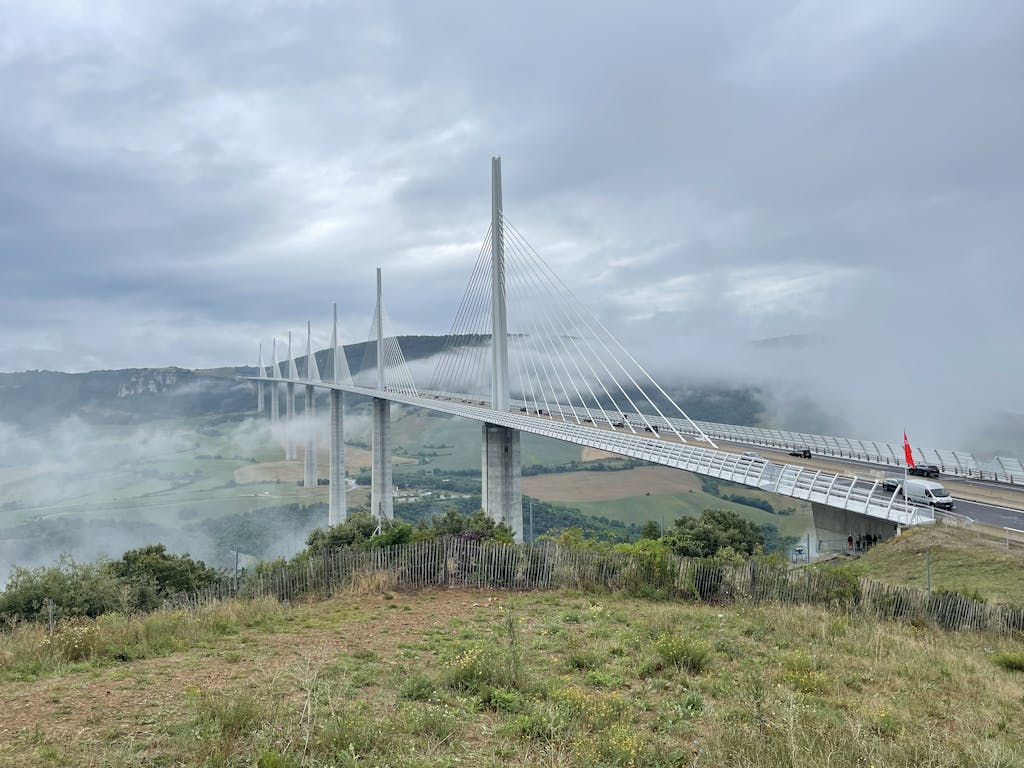 Scenic view of Millau Viaduct in Occitanie, France enveloped in fog, showcasing modern architectural beauty.