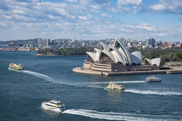 Stunning aerial photograph capturing Sydney Opera House and busy harbor ferries on a sunny day.