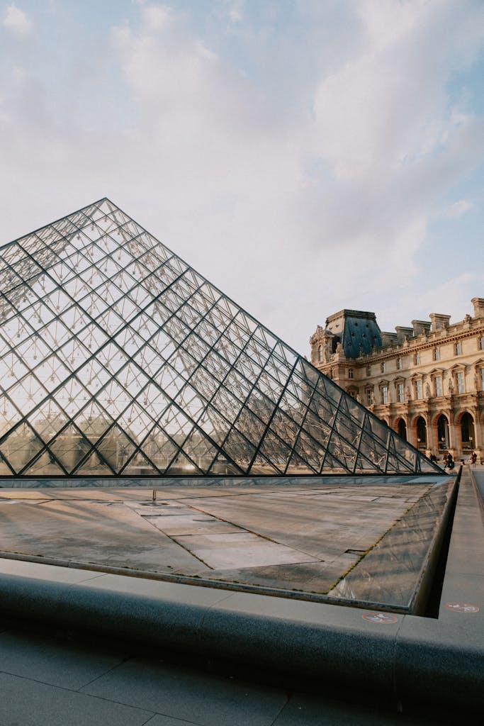 Stunning view of the Louvre Pyramid and historic museum architecture during sunset in Paris.