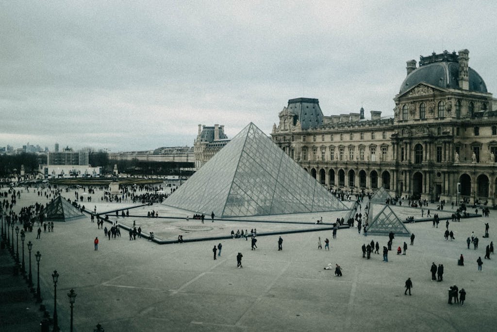 The iconic glass pyramid at the Louvre Museum in Paris during daytime.