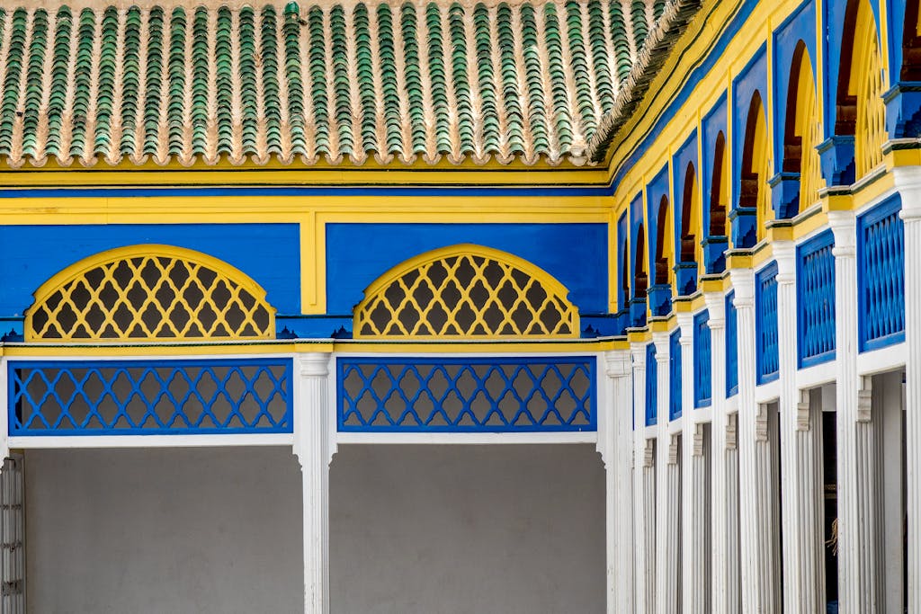 Vibrant blue and yellow ornate columns and arches of a Moroccan palace courtyard.