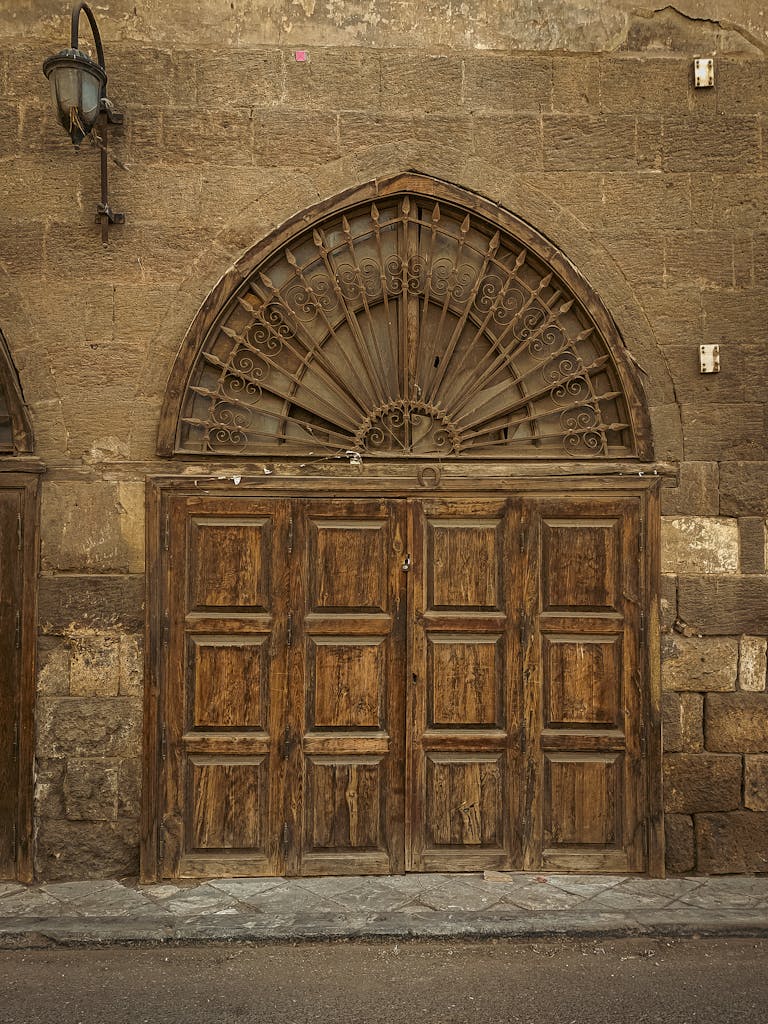 Vintage wooden door with intricate ironwork and stone facade, showcasing classic architecture.