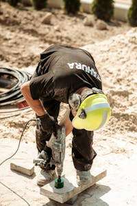Worker operates a drill on a construction site in Grójec, Poland, showcasing industry.