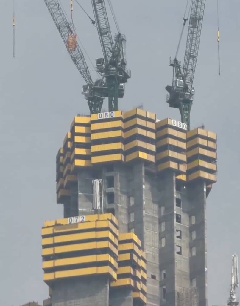 Construction work at the top of Jeddah Tower shows tower cranes and yellow self-climbing formwork systems at the 80th floor.