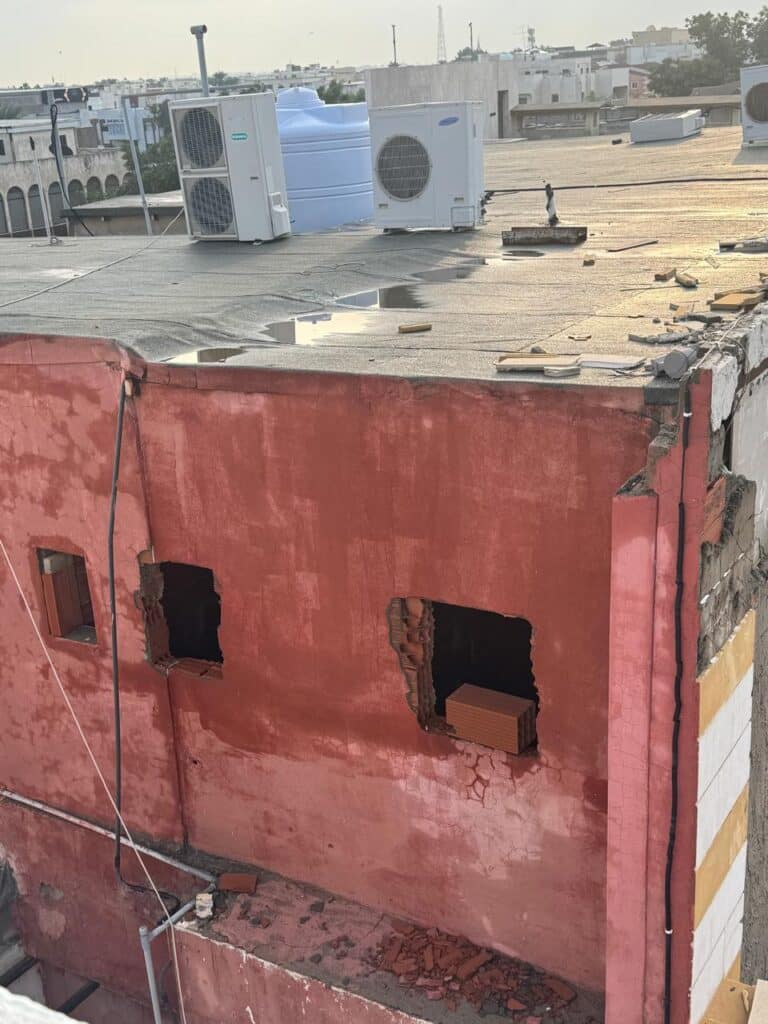 Rainwater puddling and peeling paint on a residential building roof, indicating severe waterproofing failure.