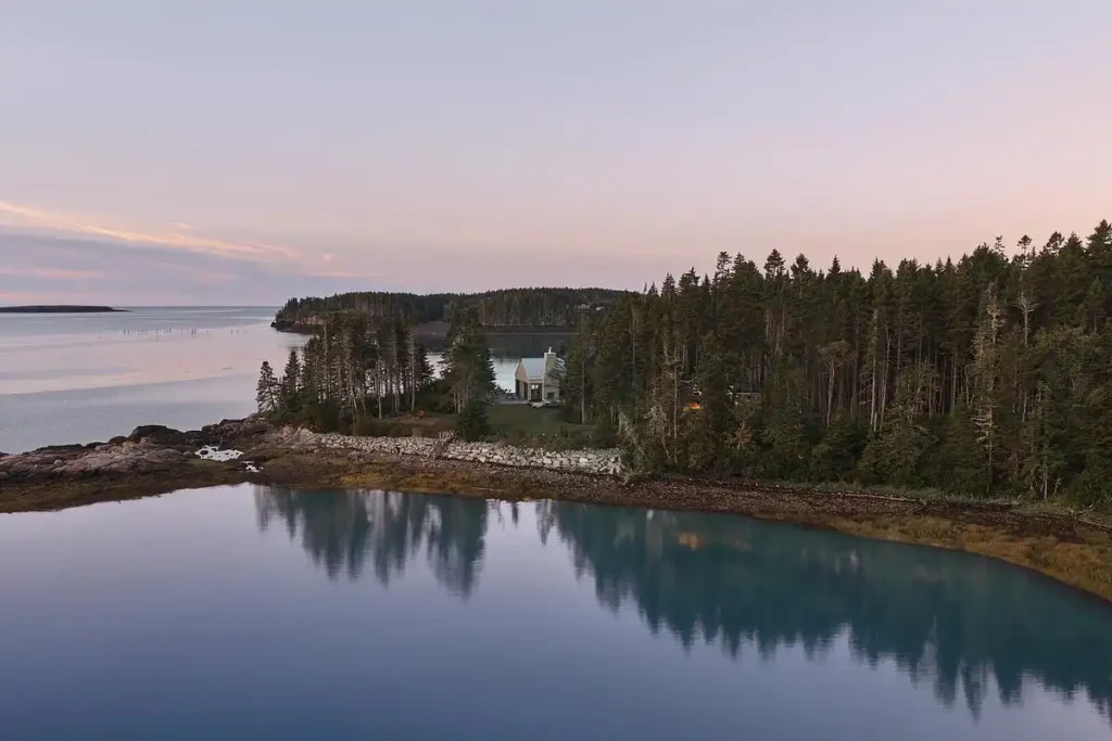 A quiet dwelling nestled between forest and sea, bathed in soft twilight.