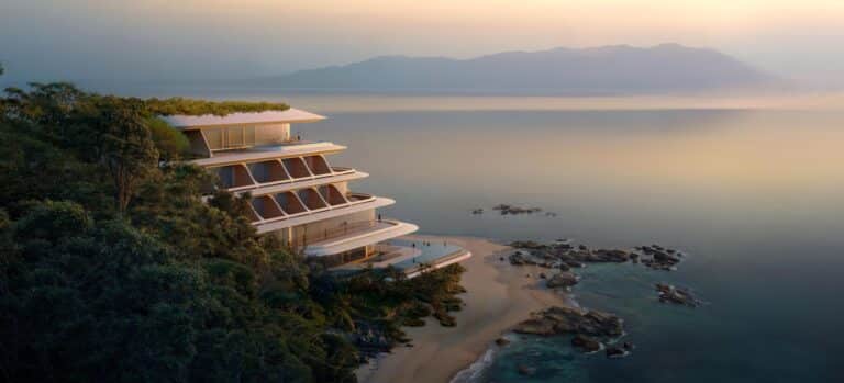 vertical hotel perched on a forested cliff overlooking turquoise waters and distant mountains at sunset