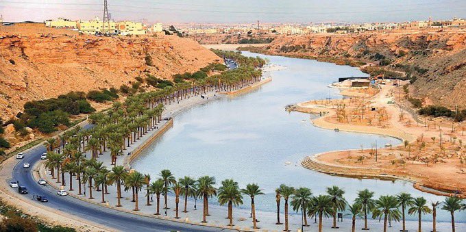 Aerial view of serpentine roads winding through the arid landscape of Dhahrat Nammar Park, with sparse greenery and vehicles navigating curves.