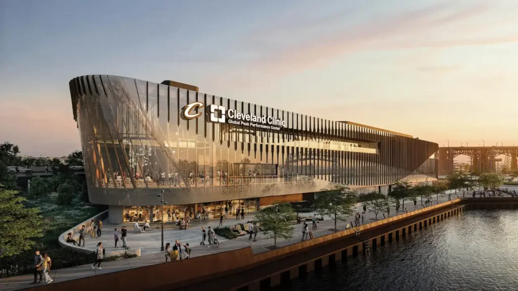 واجهة المبنى الزجاجية المتموجة تعكس ضوء الغروب وتطل مباشرة على رصيف النهر النشط.