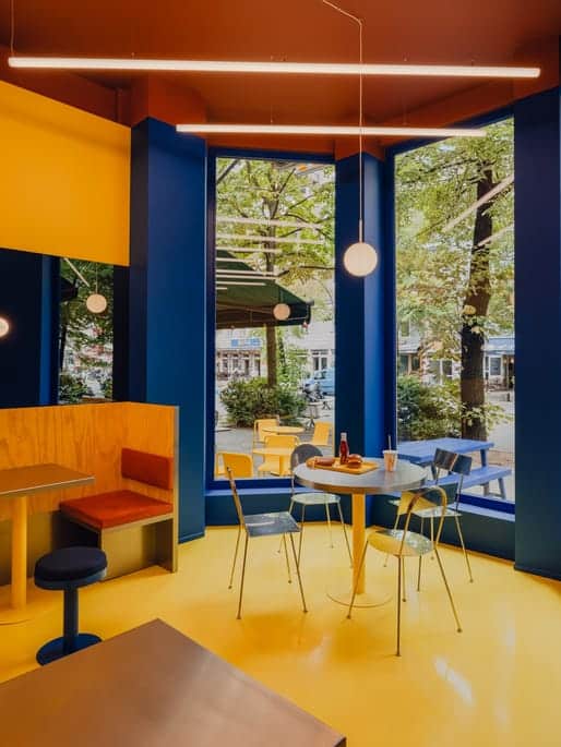 Glossy yellow floor draws visitors in, contrasted by deep blue ceiling planes.