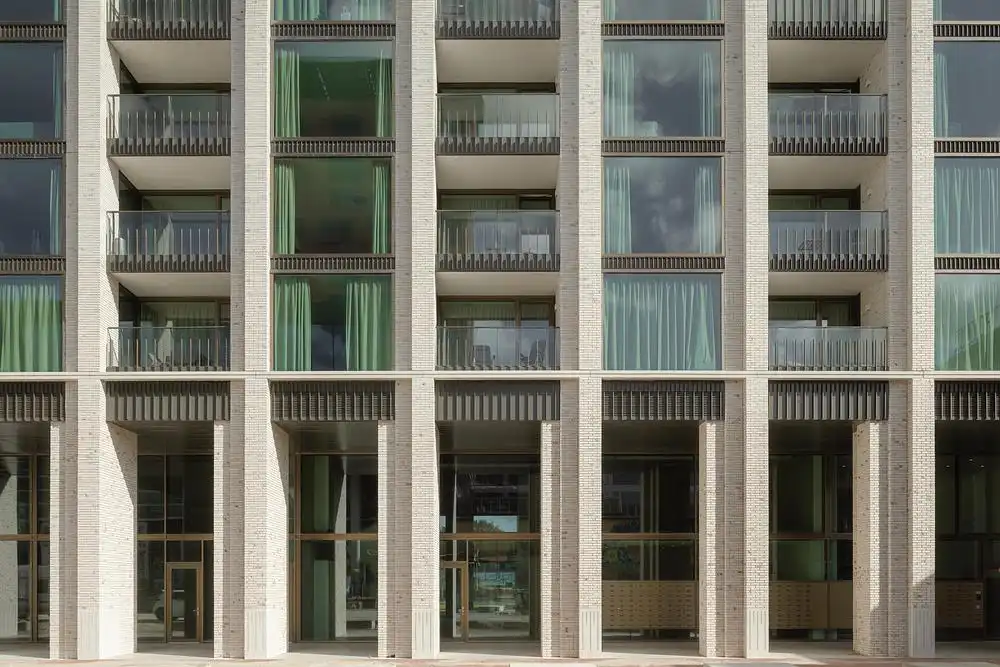 Massive brick columns create a sense of entry into the transparent, light-filled base of the building.