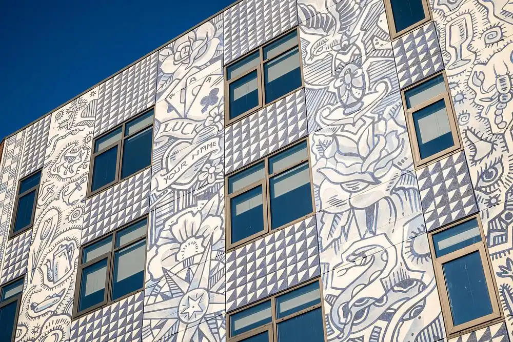 Cut-out building facade featuring a large light blue mural with nautical and floral symbols.