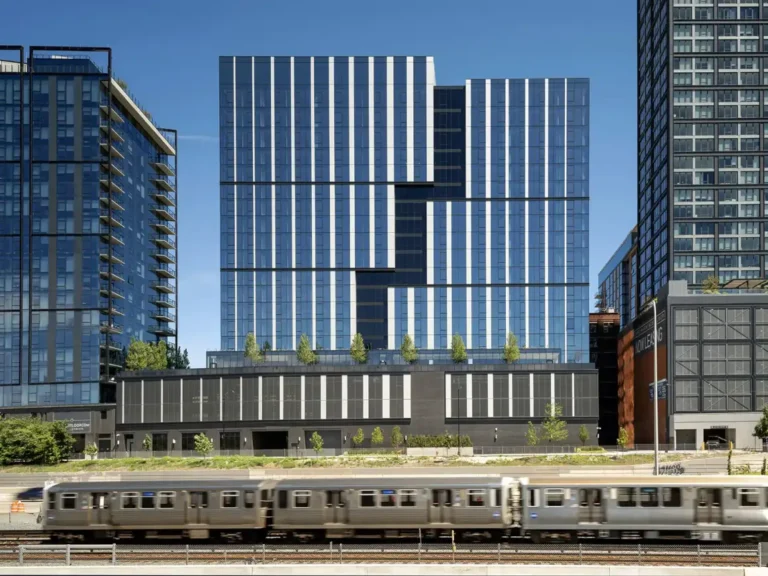 Coppia Tower in Chicago's West Loop, a 19-story mixed-use building with geometric glass façade, featuring an interstitial recess and surrounded by urban architecture under a clear blue sky.
