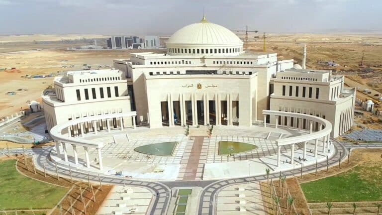 Aerial view of Egypt’s new parliament building in the New Administrative Capital, featuring a large central dome, symmetrical wings, and a circular colonnaded plaza with fountains.