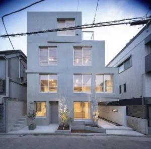 Exposed concrete facade of a multi-unit residential building in Tokyo’s Meguro ward, featuring staggered windows and minimal landscaping.