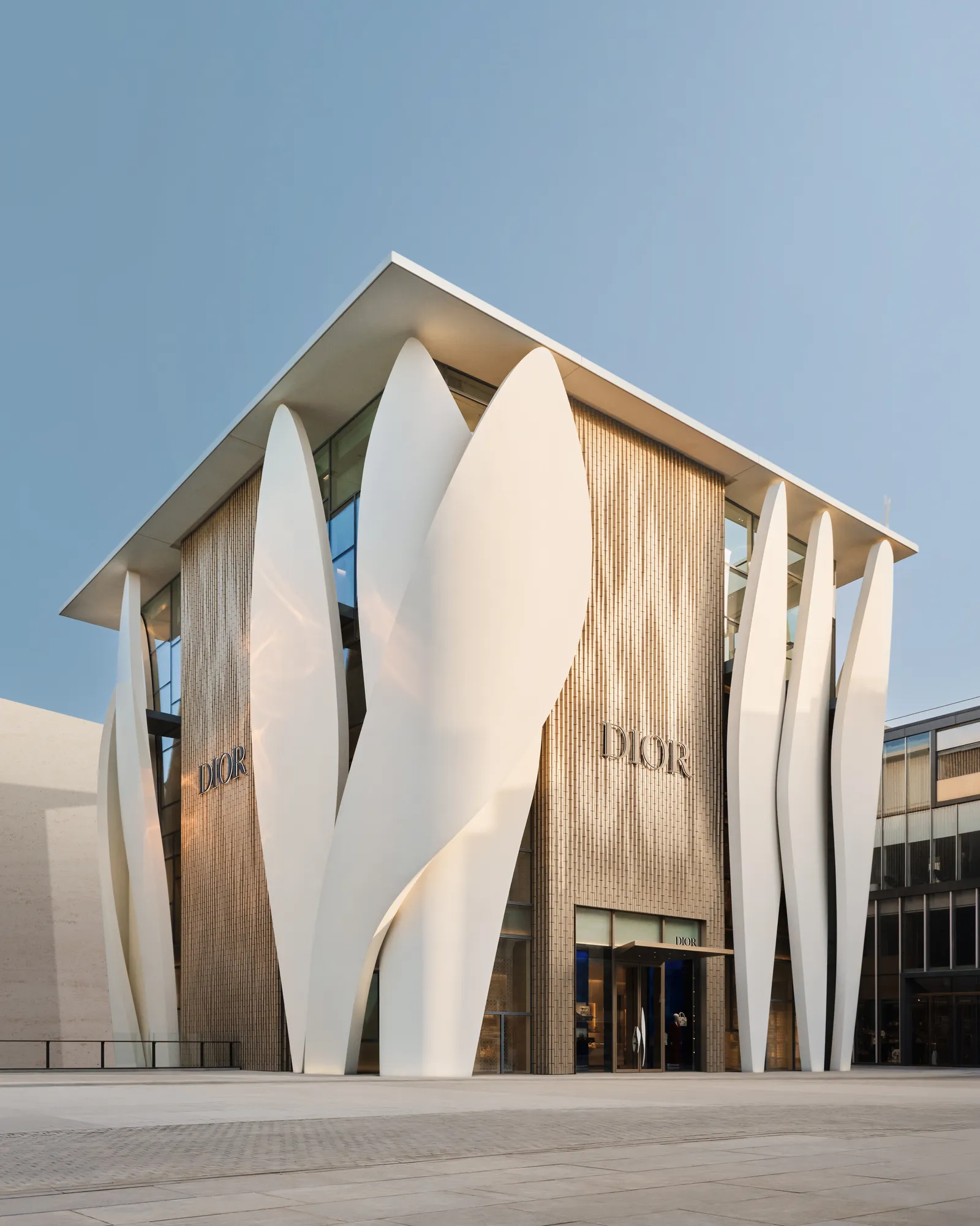 White sculptural facade of a luxury retail building in Beijing with petal-like forms and golden cladding.