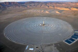 Aerial view of the world’s largest renewable energy farm after China, located in Bisha, Saudi Arabia, featuring a massive circular solar thermal array with concentric mirror fields and central tower, set against arid desert terrain.