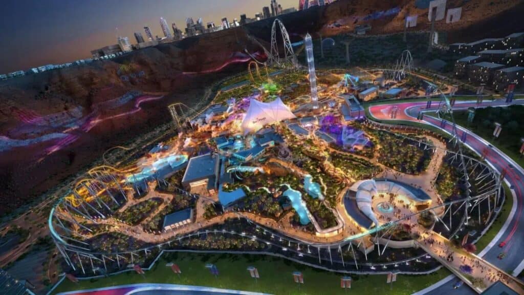 An aerial concept rendering of Six Flags Qiddiya City in Saudi Arabia at night, featuring glowing roller coasters, a central white tent structure, and a futuristic cityscape perched on the surrounding desert cliffs.