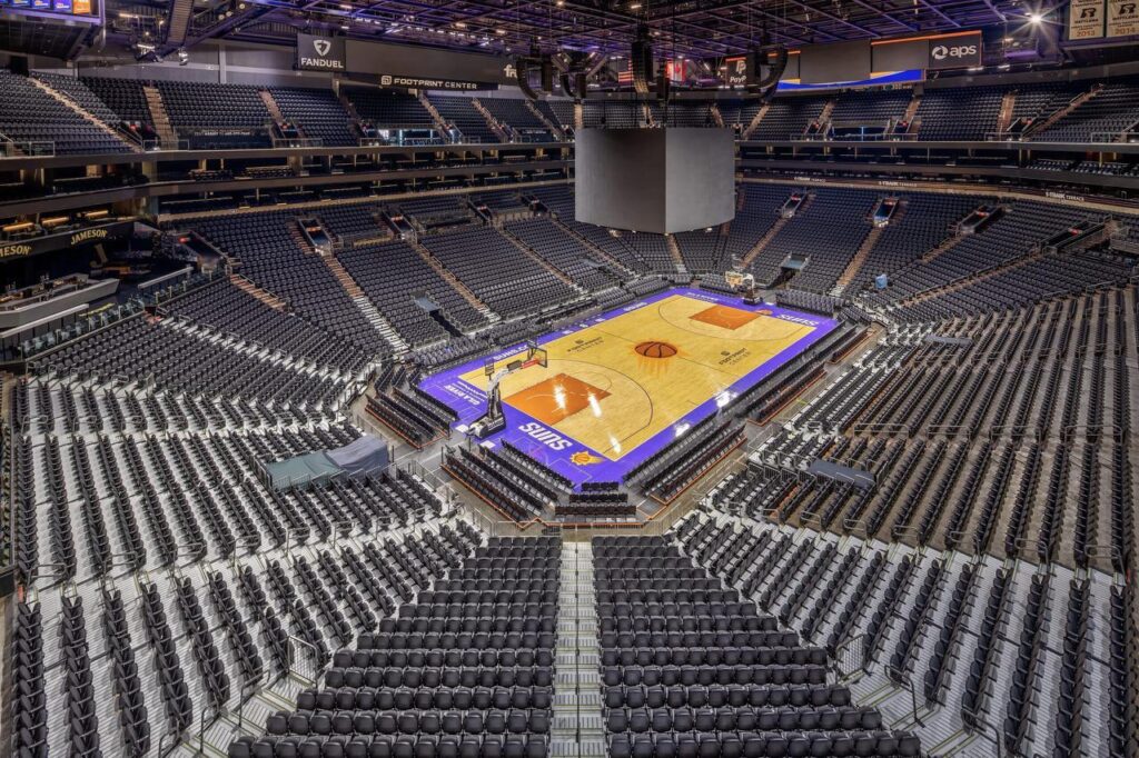 Empty indoor arena with tiered seating and basketball court, showcasing event infrastructure design for large scale sports and entertainment venues.