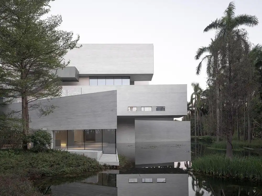 Undulating concrete masses emerging from the grove, the site-poured fa&ccedil;ade reflects a subtle texture onto the quiet water surface.