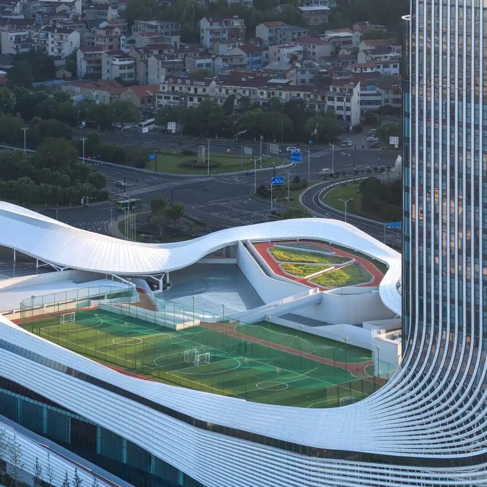 Red running track curves over the planted roof, integrating fitness with the surrounding urban context.