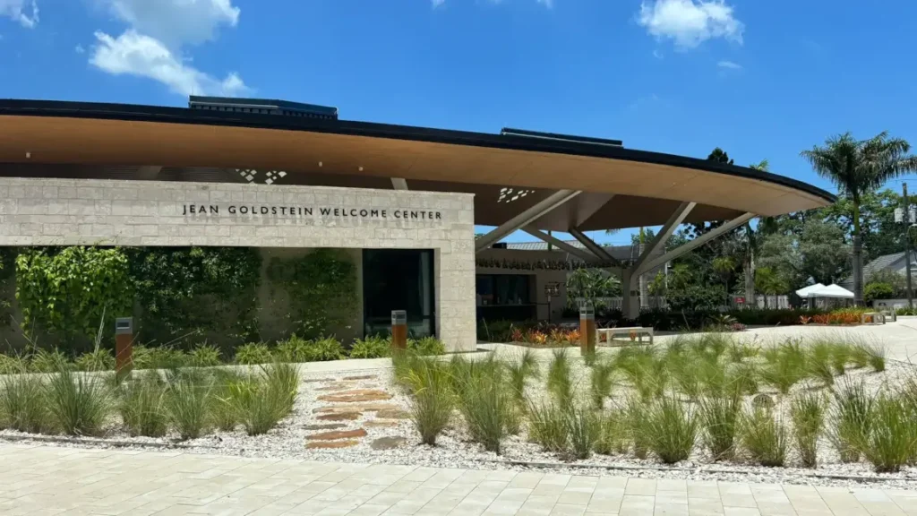 Wide promenade connects the campus, surrounded by a gradient of native plants under sunlight.