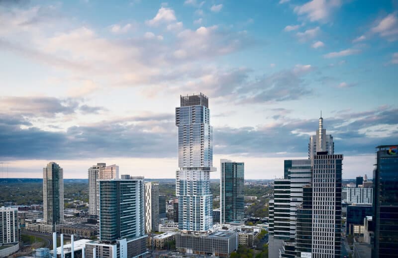 Austin residential tower dominates skyline with cantilevered form and glass facade, reflecting urban density and modern architectural design in Texas.