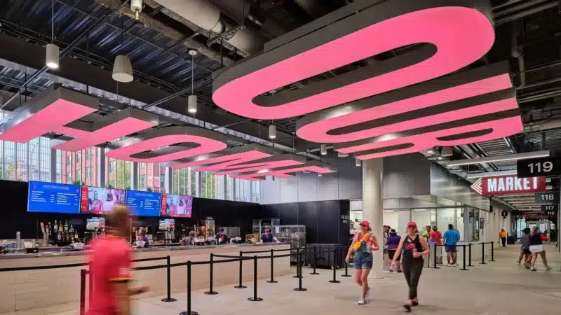 Vibrant interior design of the stadium concourse, high ceilings with bold illumination, enhancing visitor flow and fostering a sense of belonging.
