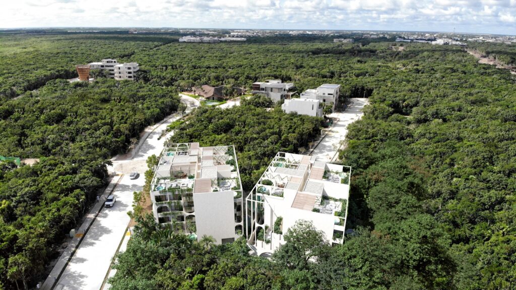 Aerial view of Vernal Tulum&rsquo;s dual towers showcasing biophilic architecture nestled within dense tropical forest.
