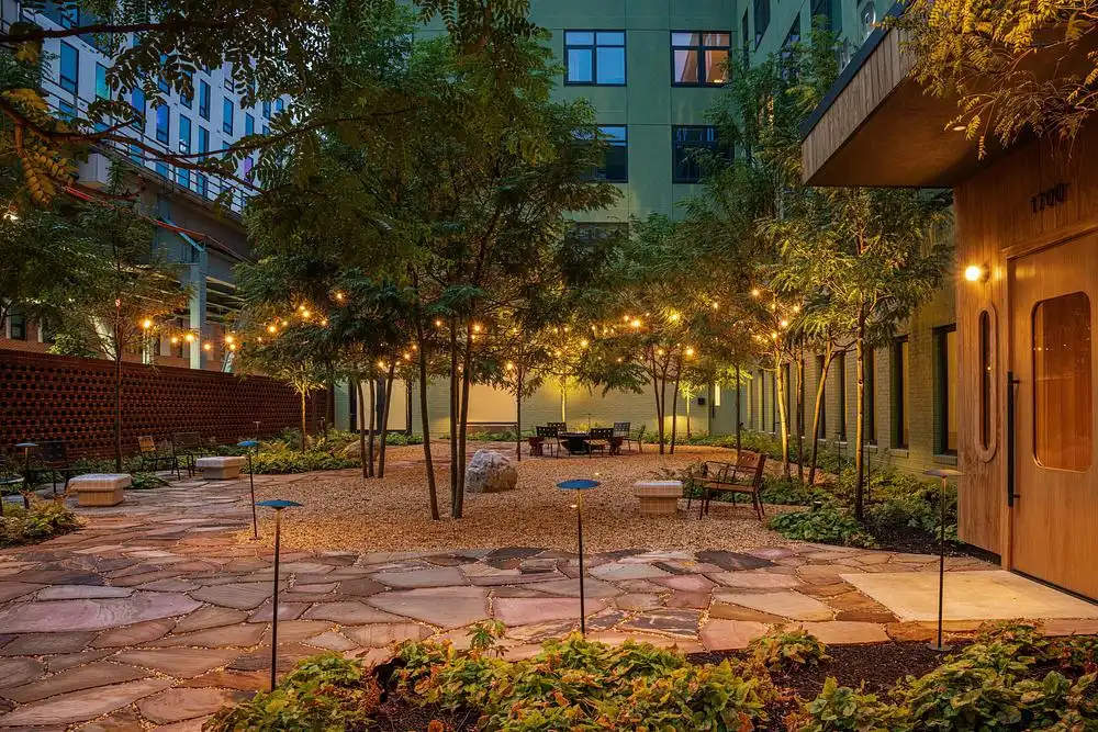 فناء حجري مُنظم بالحصى وأشجار صغيرة مضاءة بخيوط من المصابيح المتدلية.