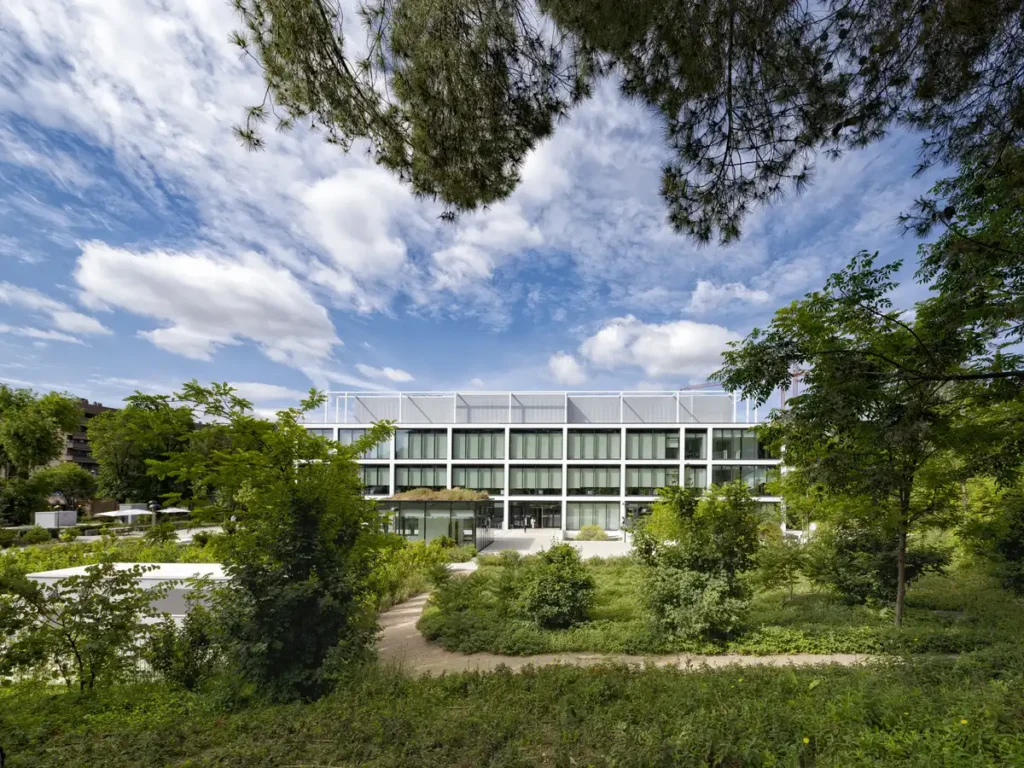 Exterior shot of the office building, surrounded by pine trees and dense greenery, confirming the integration of architecture with the regenerative landscape of the Sustainable Headquarters Design.