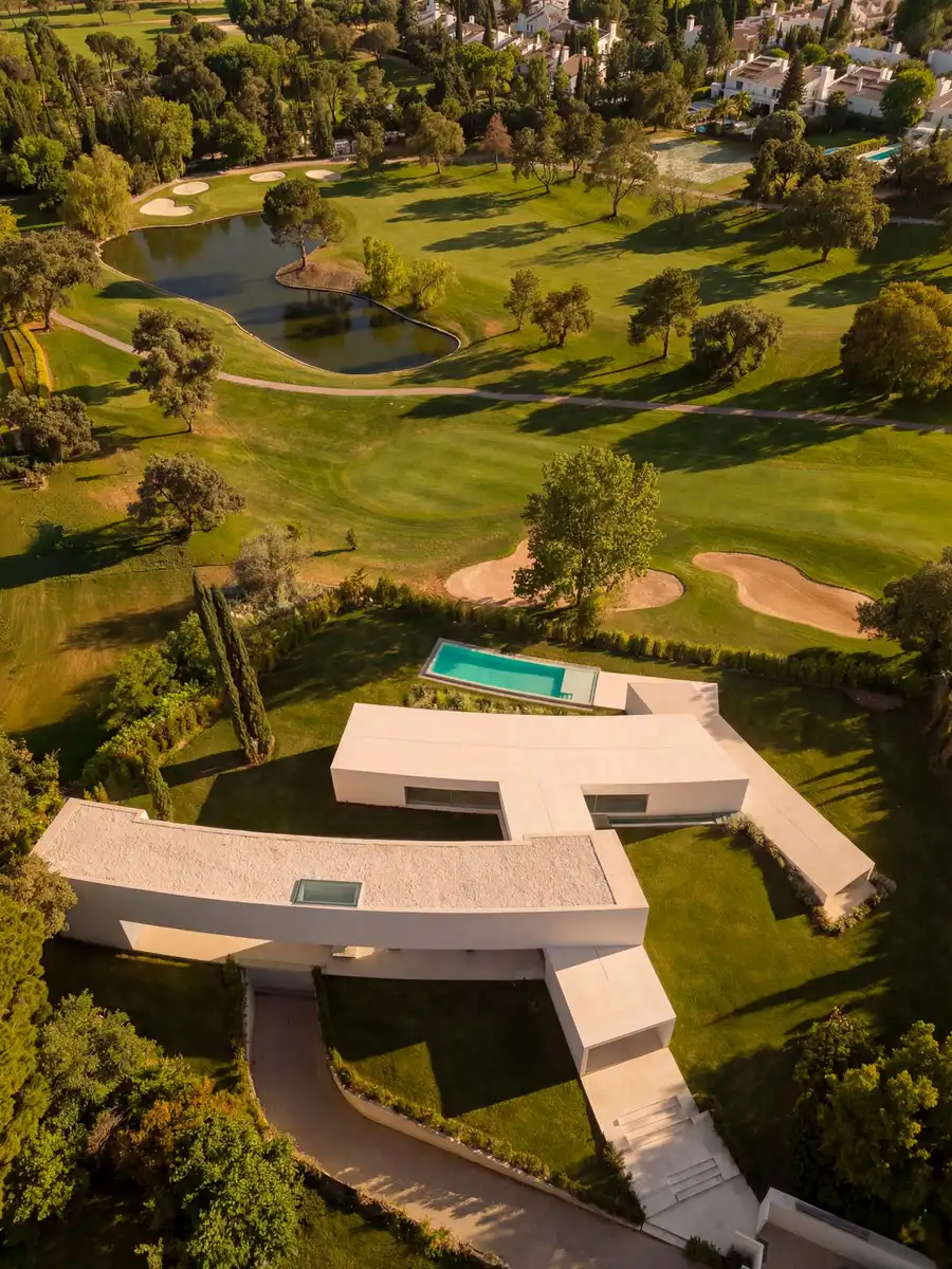 A house that melts into the garden: a modern villa in Madrid blending with a golf course through curved architectural ribbons and extended green spaces.