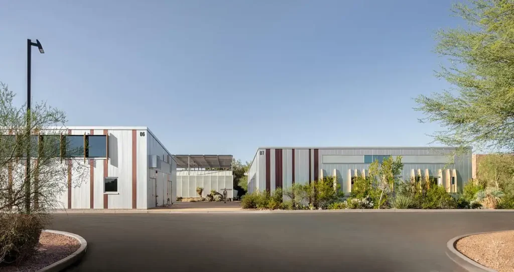Exterior view of Buildings 06 and 07  for Plant Science Phase II in Phoenix, featuring white metal cladding with vertical copper accents under a clear desert sky.
