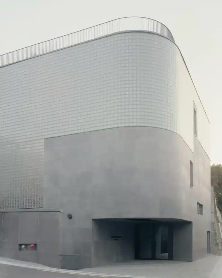 منظر خارجي لمتجر وويماند لعلامة وويونغمي في سيول، يظهر واجهة منحنية مغطاة بكتل زجاجية شفافة وقاعدة خرسانية رمادية ذات ملمس.