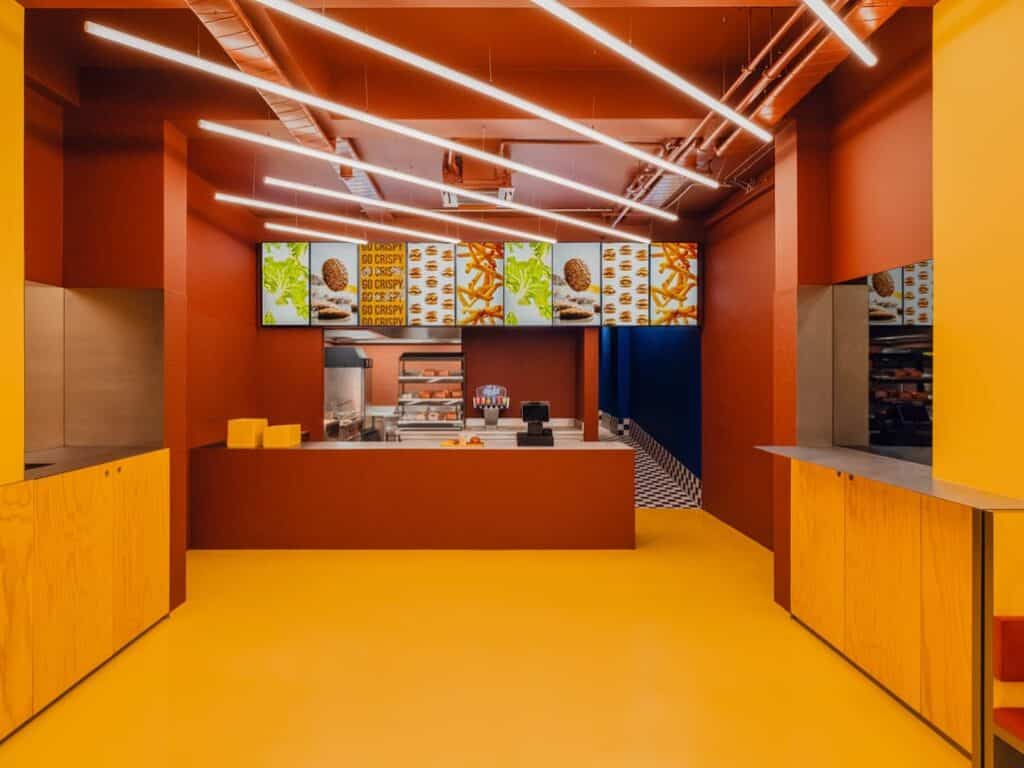 Yellow floor guides eyes to the red counter, linear lights accentuating the warm color gradient.