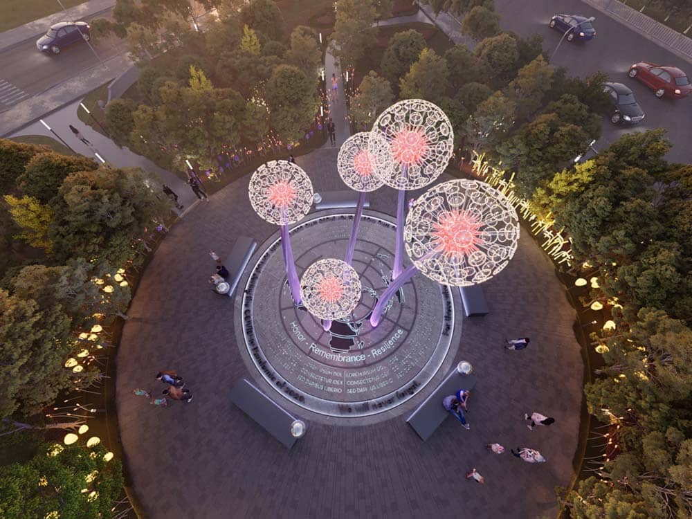 منظر علوي لهيكل النصب التذكاري لكوفيد-19 يضم أشكالاً مضيئة تشبه الهندباء ومقاعد دائرية مدمجة.