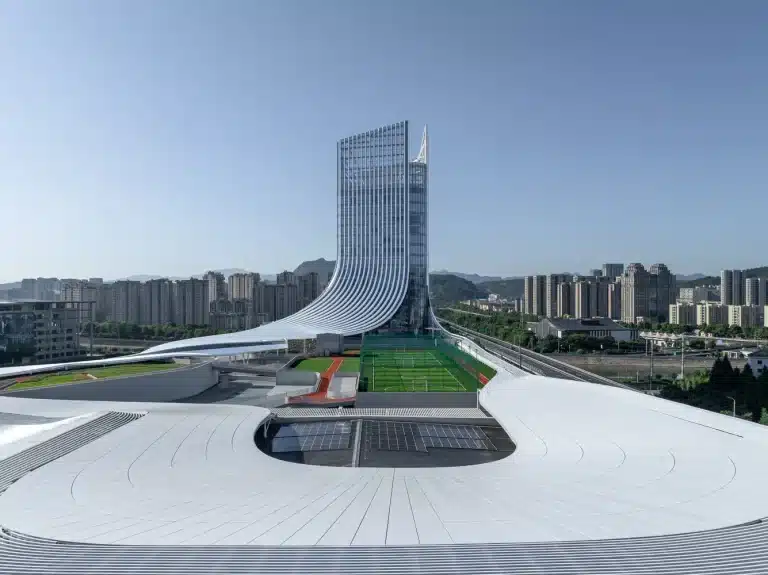 Extended white roof massing merges with mountains, as the glass tower rises to define the skyline.