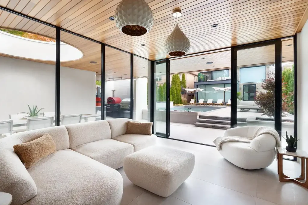 Glass-enclosed living room of the Backyard Sanctuary featuring cedar wood ceilings and a luminous circular oculus.