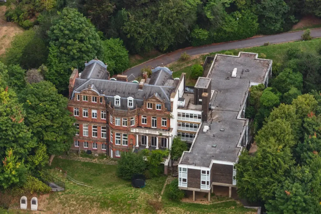 Aerial photograph of the Branch Hill House site pre redevelopment, contrasting the ornate Edwardian mansion with the unadorned, flat roofed 1960s modern wing slated for demolition.