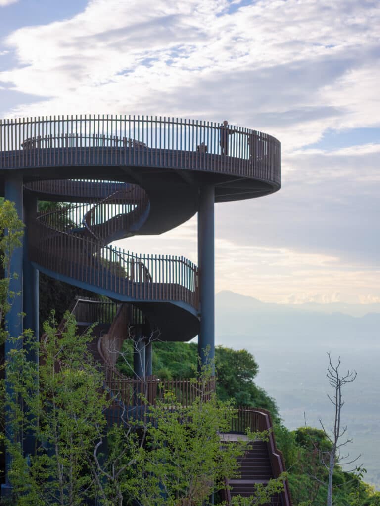 Pujiang Platform in Chengdu, an illuminated timber spiral walkway rising above the hills with views of the misty Qionglai Mountains.